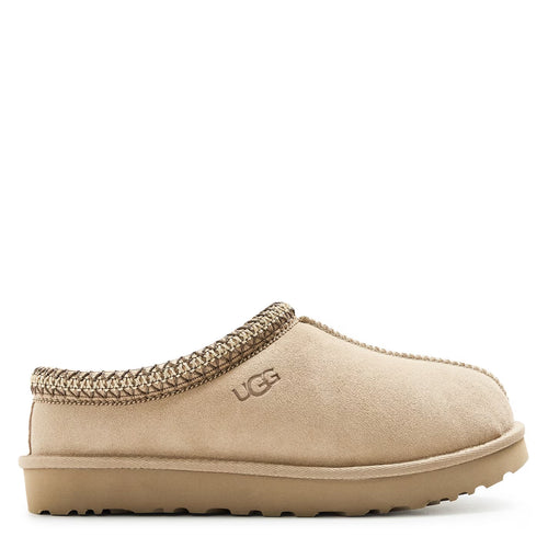 Beige UGG slipper with brown trim on a white background